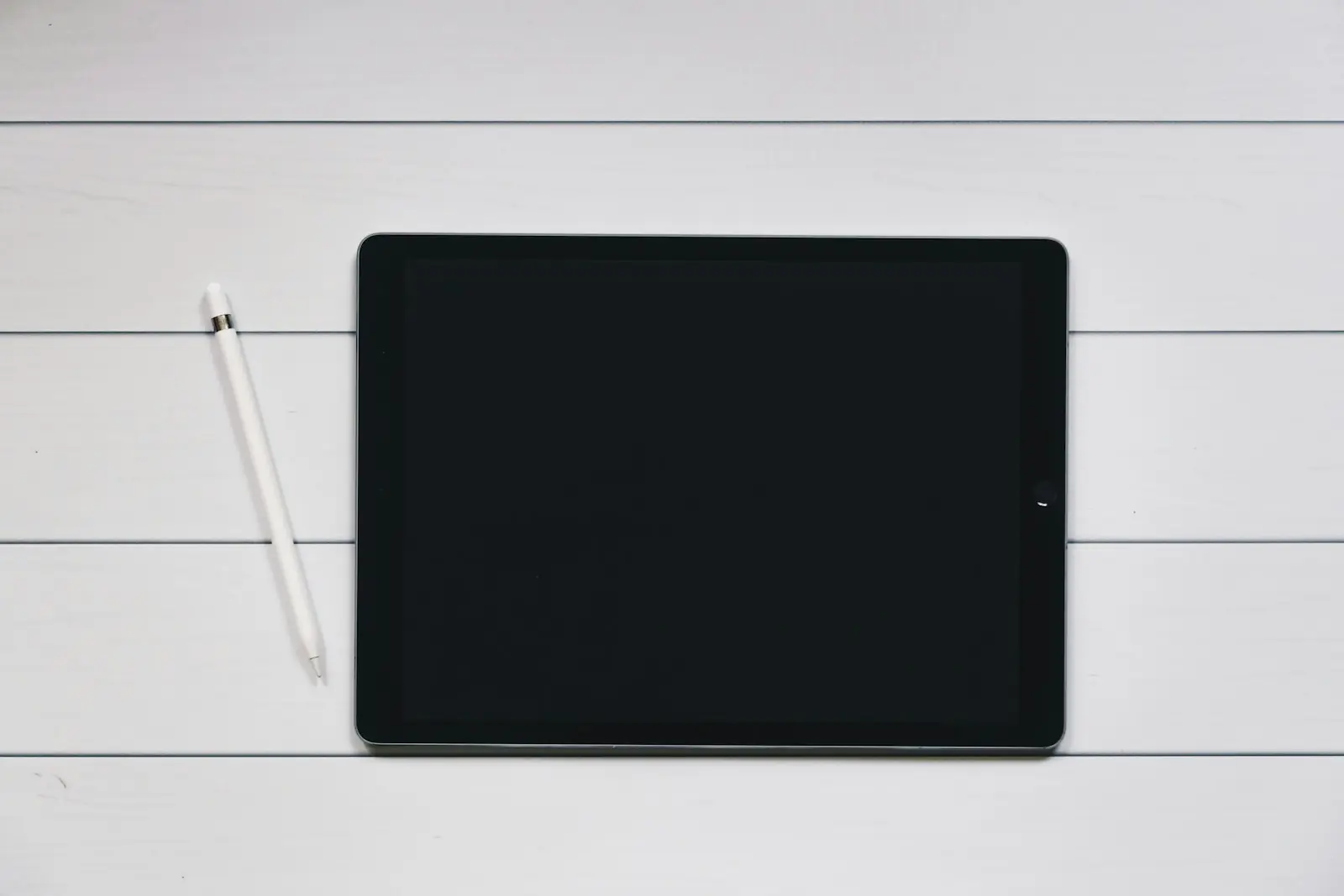 Tablet mit Eingabestift auf einem hellen Holztisch
