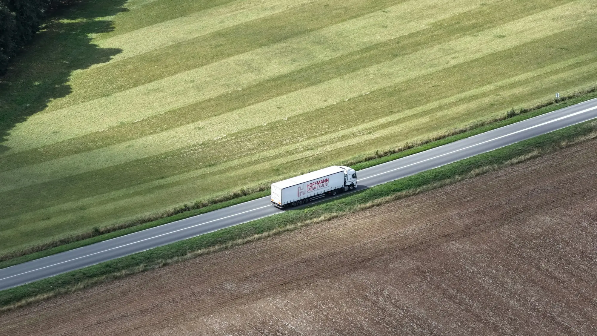 Lastwagen auf einer Landstraße zwischen Feldern, von oben fotografiert